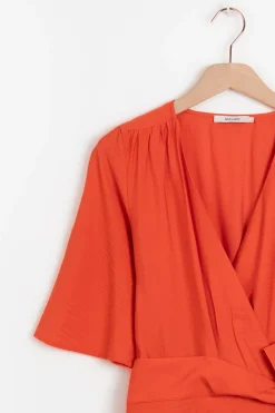 Warm oranje overslagjurk met fladdermouwen