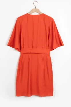 Warm oranje overslagjurk met fladdermouwen